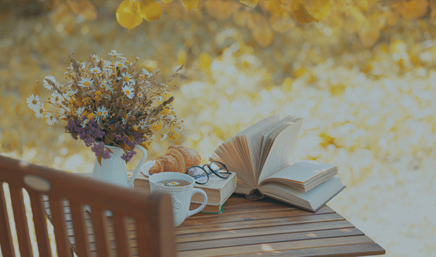 Bouquet of flowers next to a croissant and a cup of tea or coffee