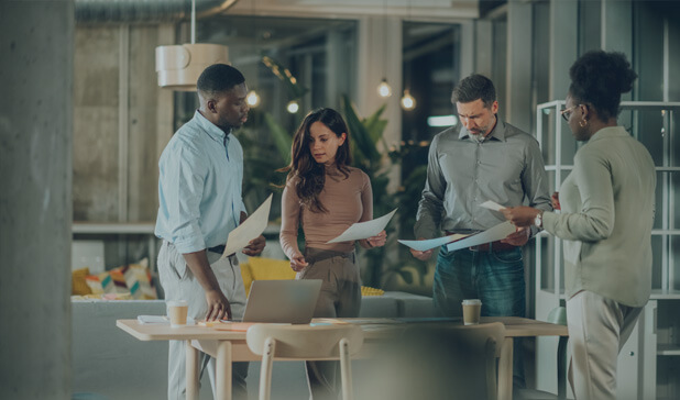 A diverse group of business professionals is discussing documents together.
