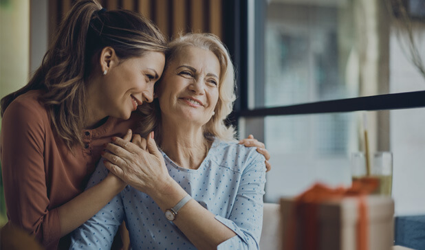 Happy senior woman enjoying her daughter’s affection and warmth