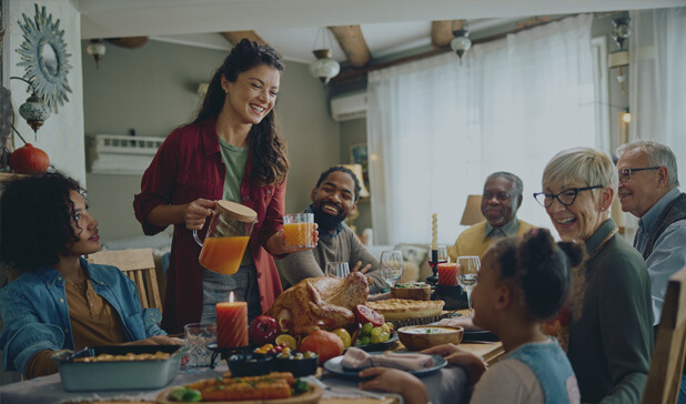 Happy woman serving drinks to her multigeneration family.